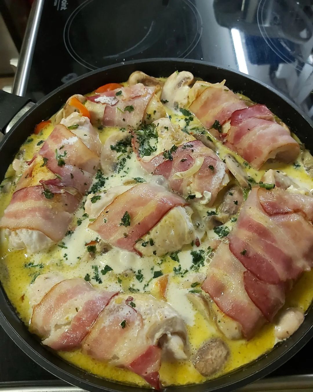 Куриная грудка, смазанная творожным сыром, закрученная в бекон, с перцем, луком и шампиньонами в сливках.