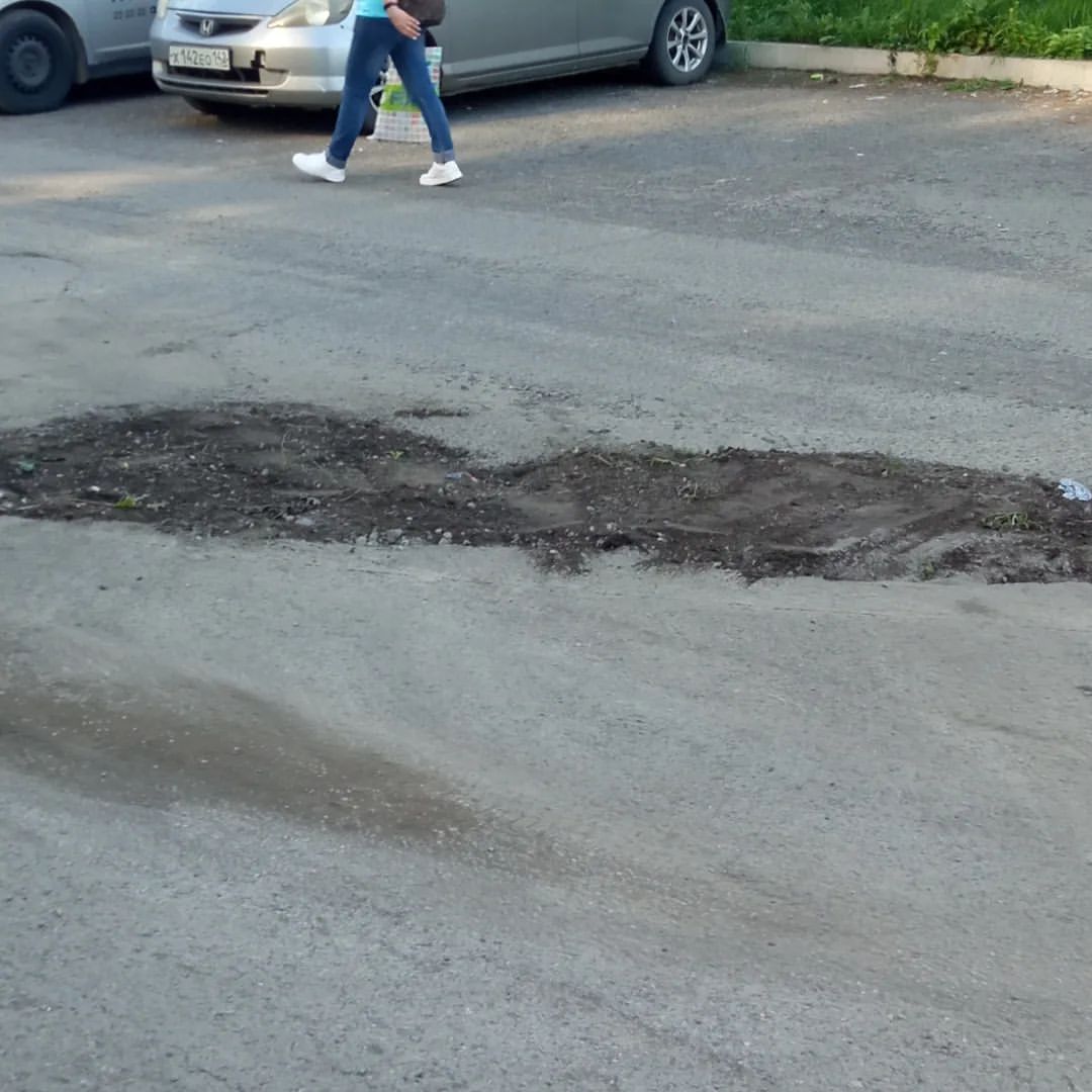 В Новоильинском районе дорожные ямы заделывают землёй. На этом участке очень большое количество машин.  Между домами Косыгина 65 и Косыгина 75.