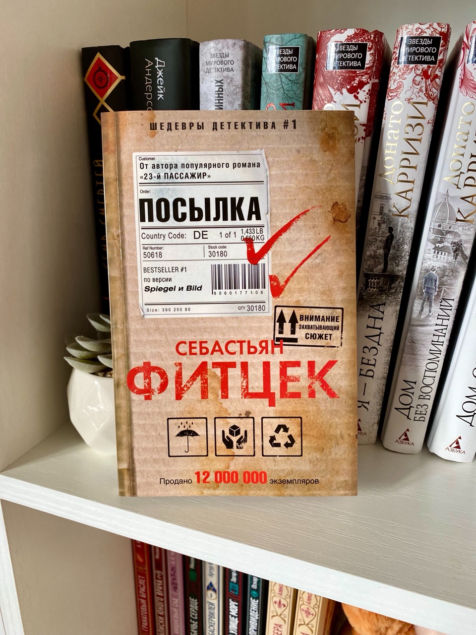 📦 Посылка
Себастьян Фитцек
18+
3/5
Типичный представитель напряжённого психологического триллера в духе Фитцека: мрачная атмосфера, игра с восприятием реальности и постоянное ощущение, что за героем кто‑то следит. С первых страниц автор ловко цепляет внимание: обычная, казалось бы, просьба принять посылку для незнакомого соседа запускает цепочку пугающих событий и вскрывает глубокие психологические травмы главной героини.
Особенно хорошо Фитцек работает с состоянием паранойи. Он не просто рассказывает о страхе героини — он буквально заставляет читателя почувствовать его. Благодаря частой смене фокуса, коротким главам и резким переходам между сценами напряжение держится почти всё время. В отдельные моменты книга читается запоем: хочется как можно скорее узнать, что скрывается за очередной деталью, почему прошлое героини так настойчиво даёт о себе знать и кто стоит за странными совпадениями.
Однако ближе к середине эффект начинает ослабевать. Автор слишком часто возвращается к одним и тем же переживаниям и внутренним конфликтам героини, из‑за чего некоторые сцены начинают ощущаться как повторы. Много внимания уделено флешбэкам, и хотя они объясняют мотивацию героини, их подача местами кажется избыточной: вместо того чтобы усиливать интригу, они замедляют темп и рассеивают фокус.
Персонажи прописаны неравномерно. Главная героиня, Эмма, получилась живой и психологически достоверной: её страхи, сомнения и попытки справиться с травмой выглядят убедительно. А вот второстепенные персонажи остаются на периферии: муж, коллеги, соседи — они скорее выполняют функцию сюжетных инструментов, чем самостоятельных фигур. Из‑за этого их поступки иногда кажутся слишком удобными для развития интриги, а не продиктованными логикой характера.
Финал вызывает смешанные чувства. С одной стороны, он закрывает основные линии и даёт ответы на главные вопросы. С другой — ощущение «вау‑эффекта» не возникает: развязка скорее выглядит как логическое завершение, а не как неожиданный поворот, который переворачивает всё прочитанное с ног на голову.